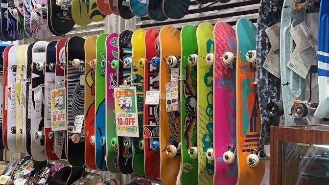 A display of colorful skateboards hanging on a wall at a skate shop, featuring various designs and price tags for discounts.